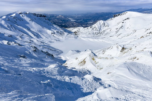 午後の光が差す安達太良山の爆裂火口と雪に覆われた冬の火口壁
