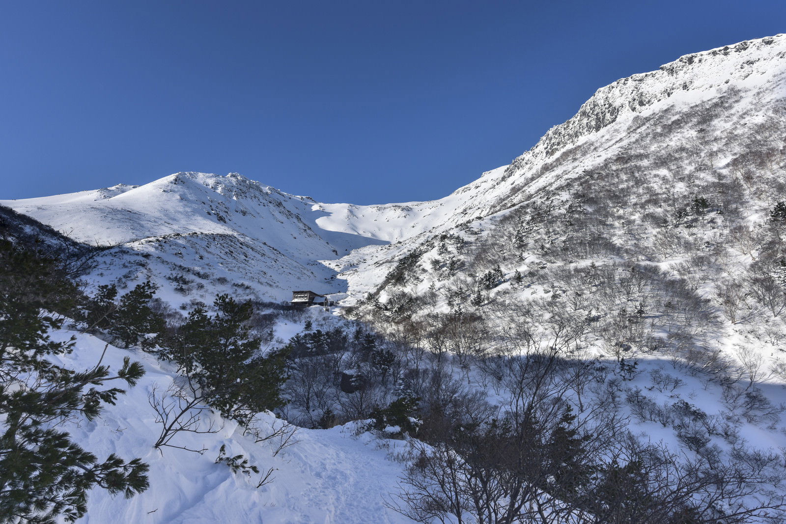 雪化粧した安達太良山とくろがね小屋を青空の下で撮影した冬山風景