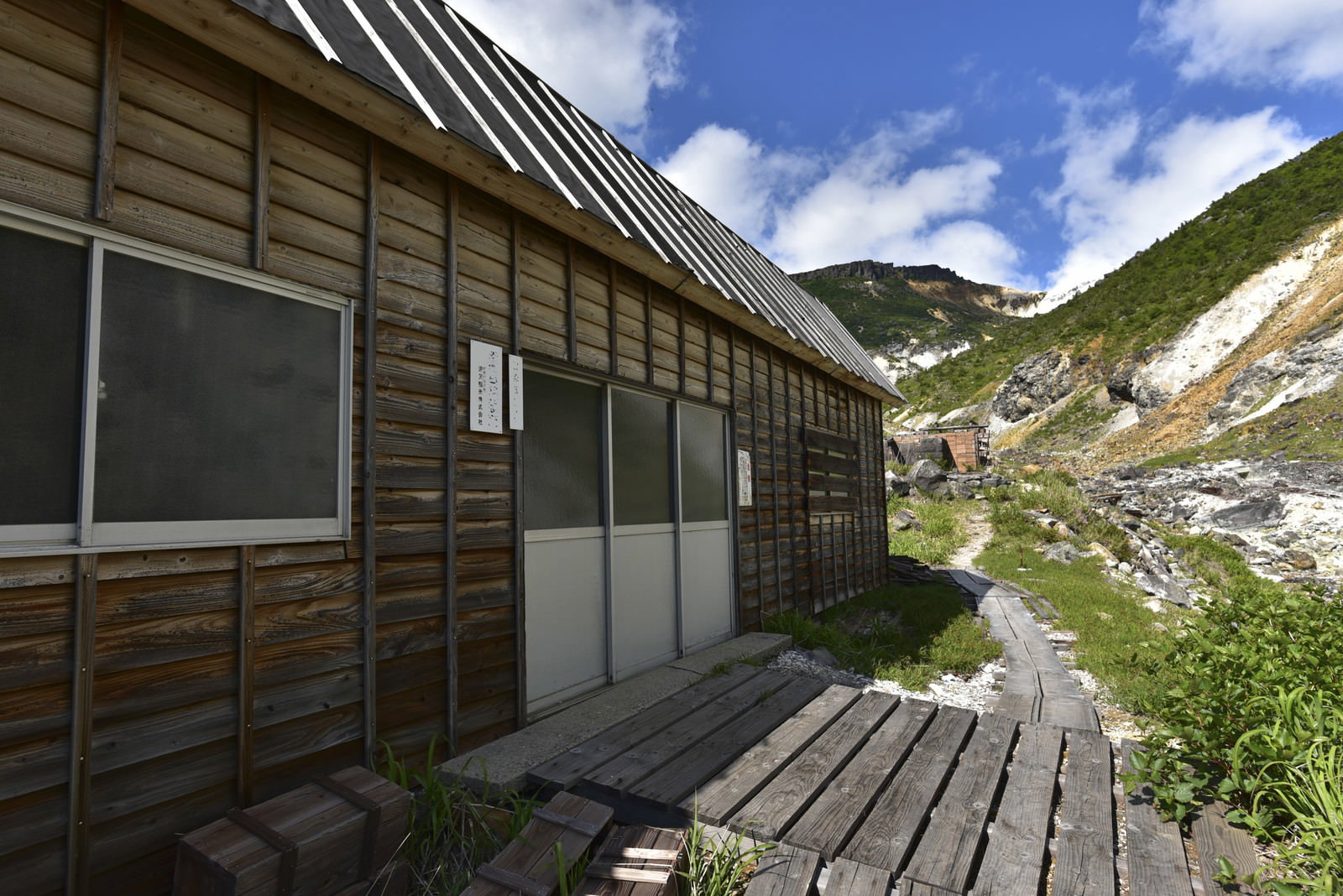 安達太良山の湯畑にある木造の山小屋と緑の山々