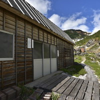 安達太良山の湯畑に建つ木造の山小屋群と温泉地の風景の写真