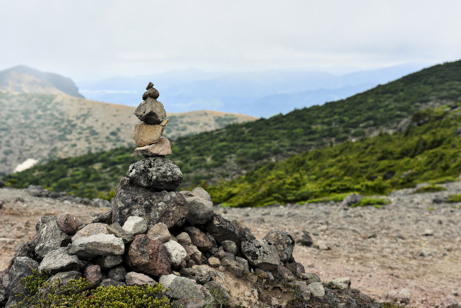 安達太良山の稜線に石を積み重ねたケルンが立つ風景