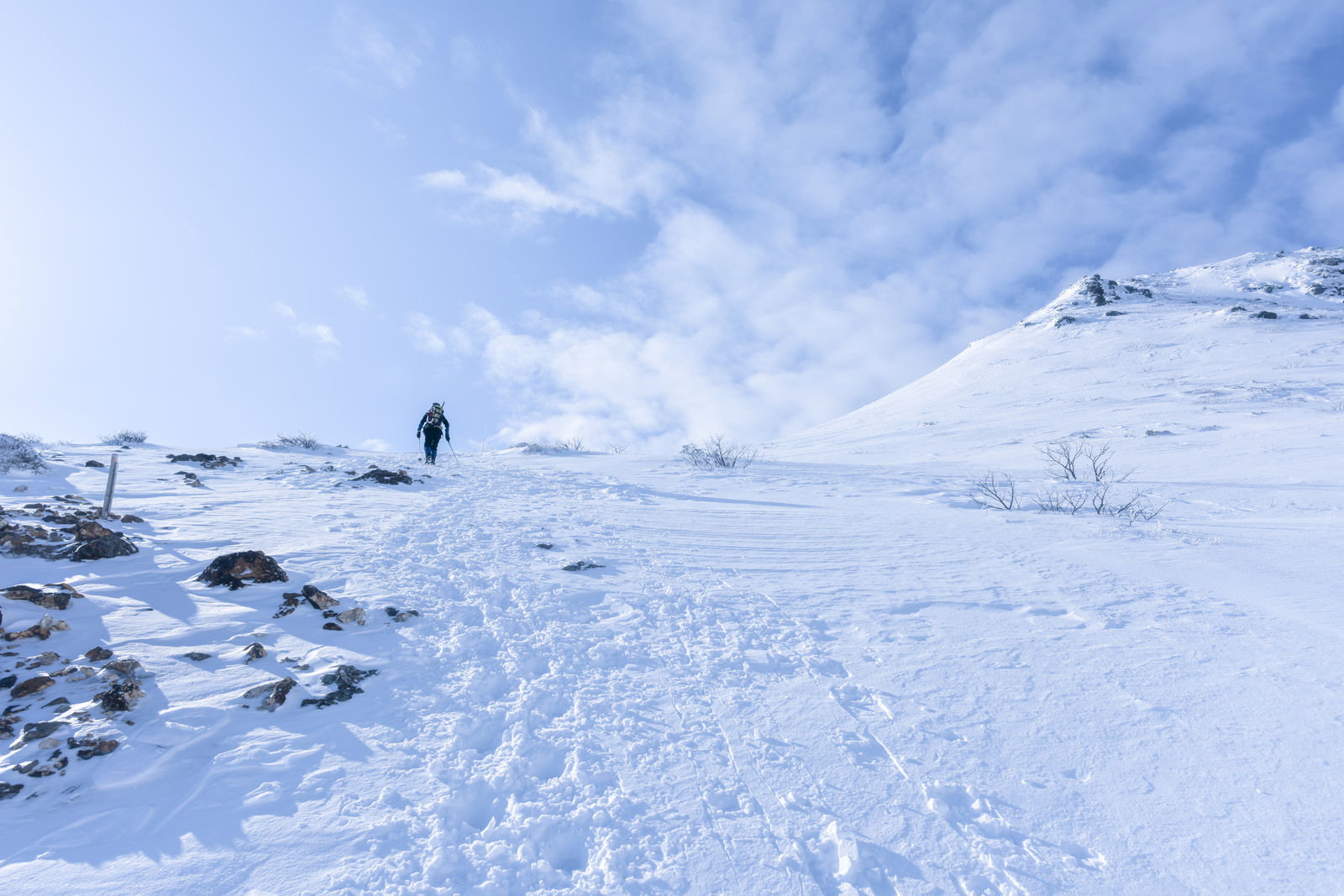 雪に覆われた安達太良山の斜面を歩く登山者と足跡が続く雪原
