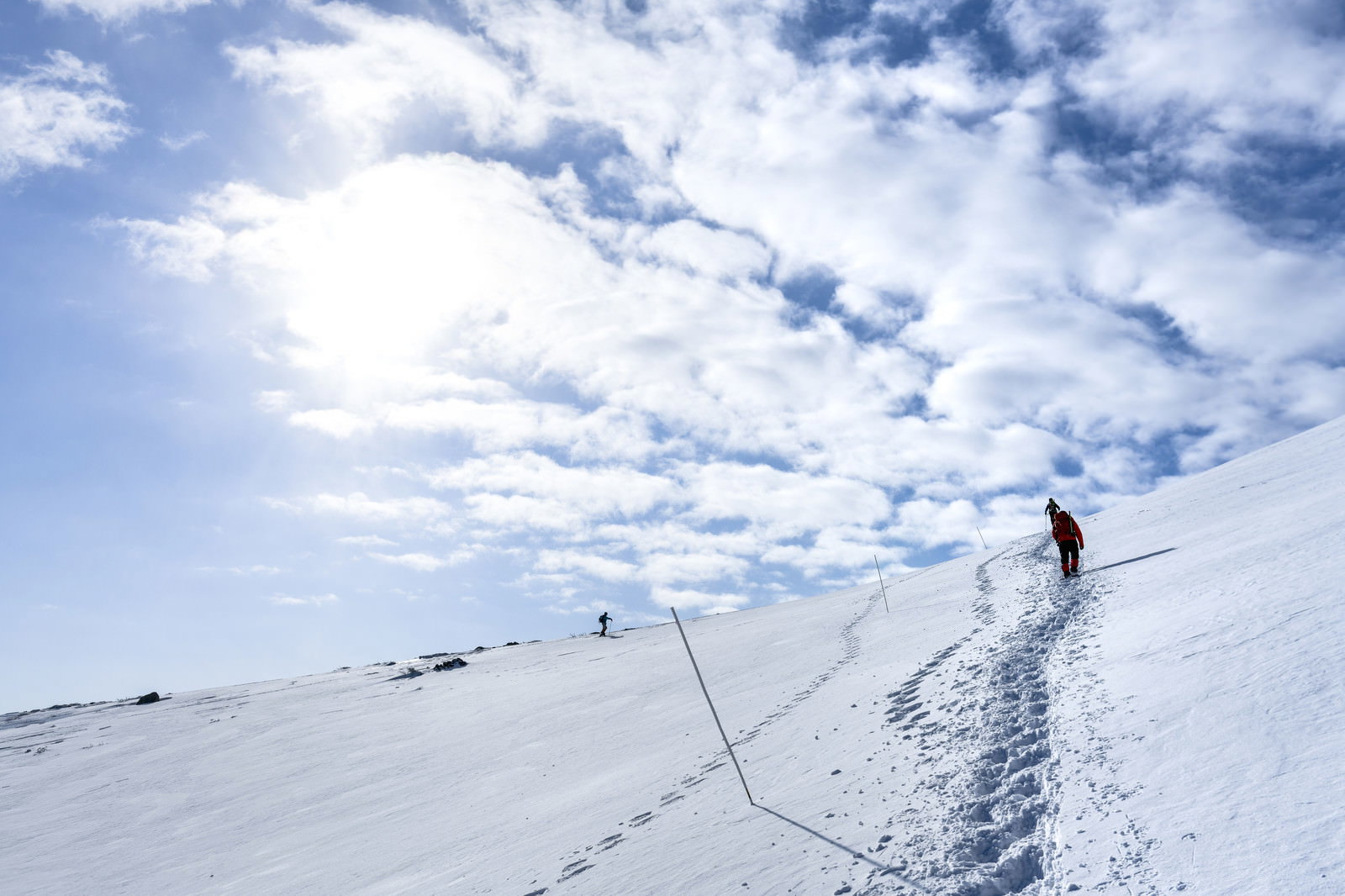雪に覆われた安達太良山の斜面を登る登山者と足跡のトレース