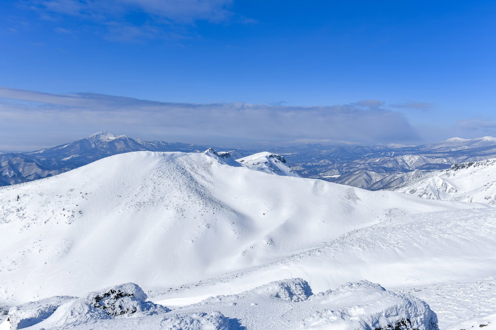 安達太良山山頂から望む雪に覆われた磐梯山と連なる山々