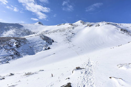 安達太良山山頂へと続く雪の登山道と登山者の足跡