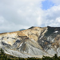 曇り空の下の安達太良山爆裂火口と荒涼とした火山地形の写真