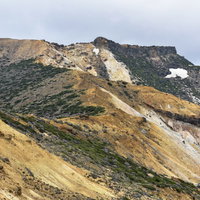 曇り空の下に広がる船明神山方面の安達太良山の荒野の写真
