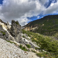 白い砂礫の斜面を下る登山者（安達太良山）の写真