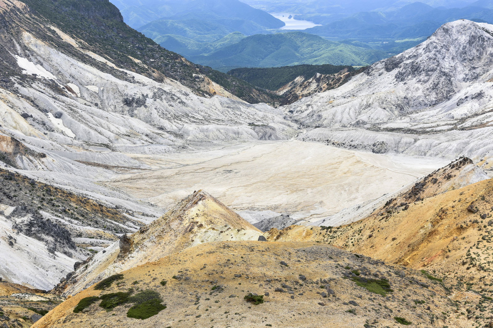 安達太良山の山頂から見下ろす爆裂火口と遠くに広がる山並み