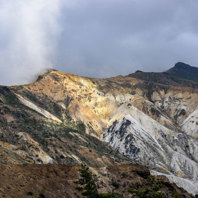 雲に包まれる安達太良山の爆裂火口と火山地形の斜面の写真