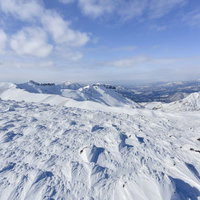 安達太良山の雪面に刻まれた風紋と船明神山方面の稜線の写真