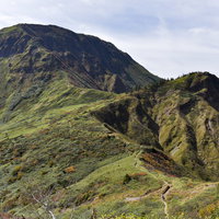 午後の日差しで陰影が強まる苗場山の稜線と緑の山肌の写真