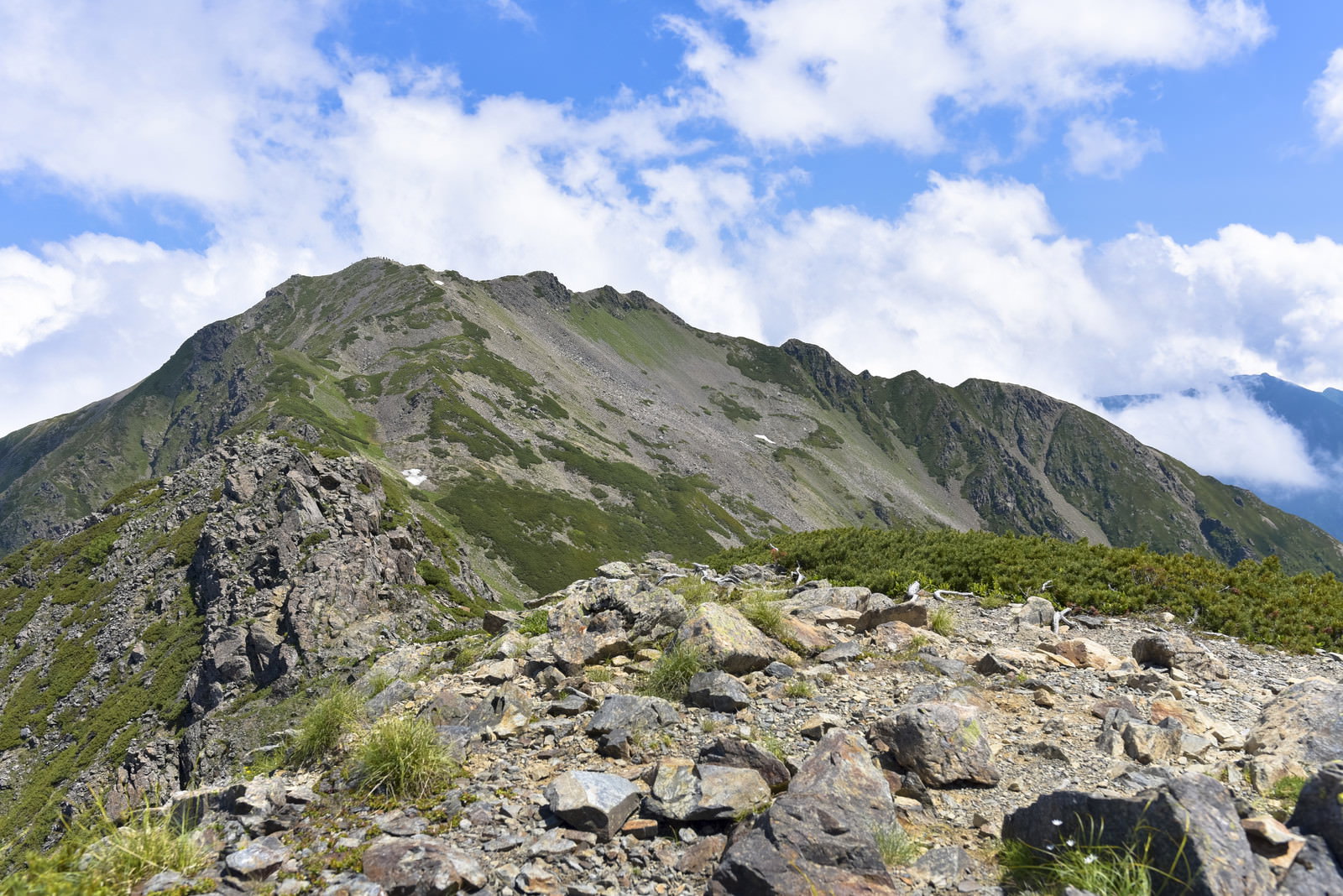 大仙丈岳の岩場から見上げる仙丈ヶ岳の山頂と青空