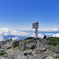 大仙丈岳山頂に佇む登山者と眼下の雲の写真