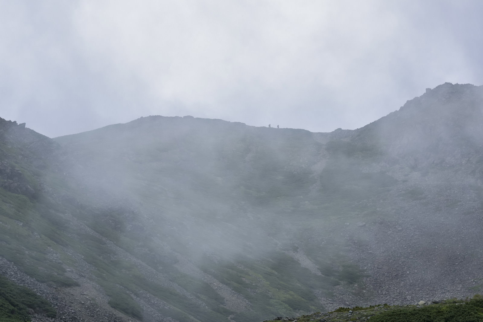 雲に包まれた仙丈ヶ岳の稜線を歩く登山者たち