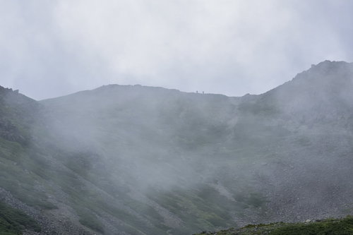 雲に包まれる仙丈ヶ岳の稜線を歩く登山者たち