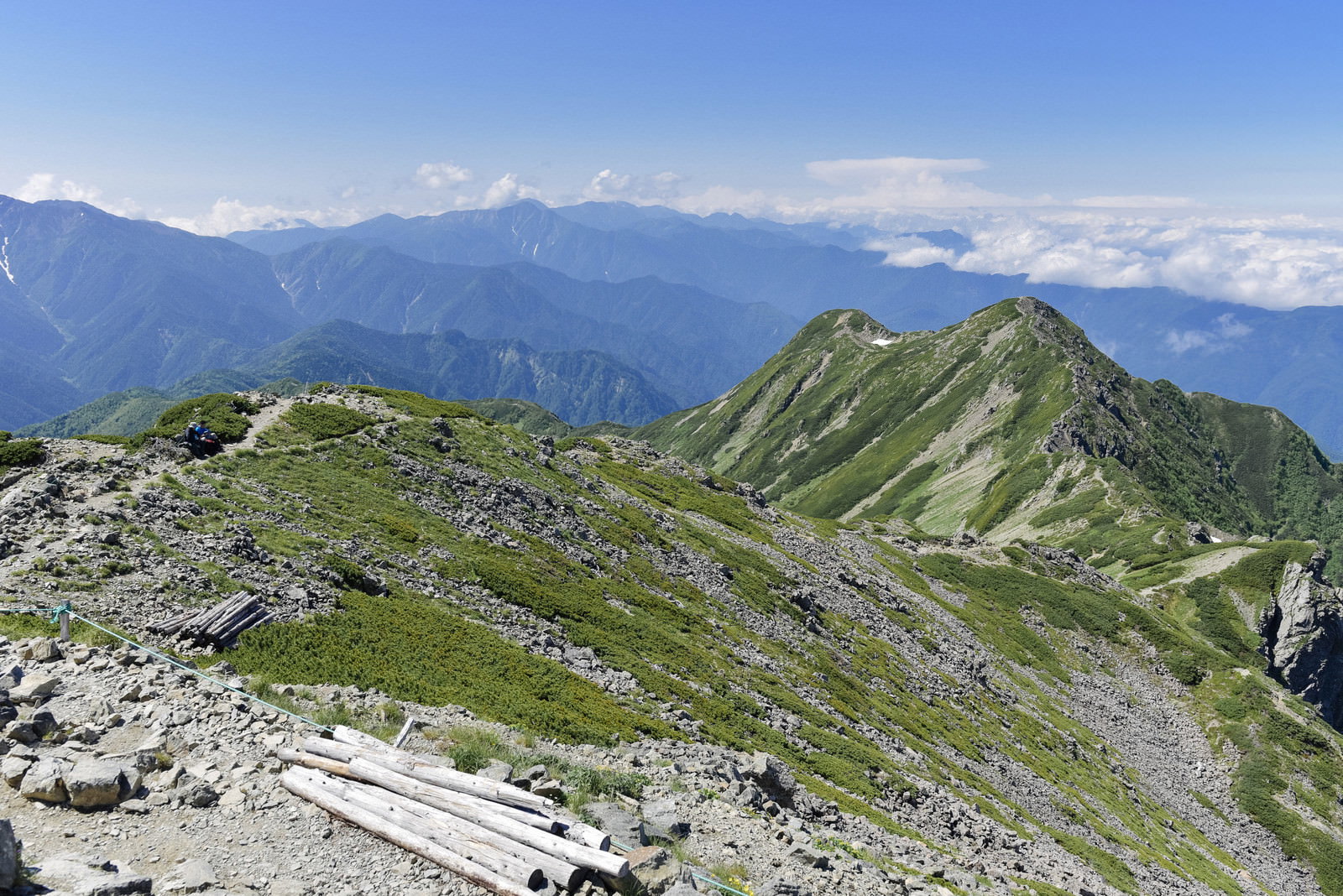 青空の下に広がる南アルプスの緑豊かな山々と大仙丈ヶ岳の稜線
