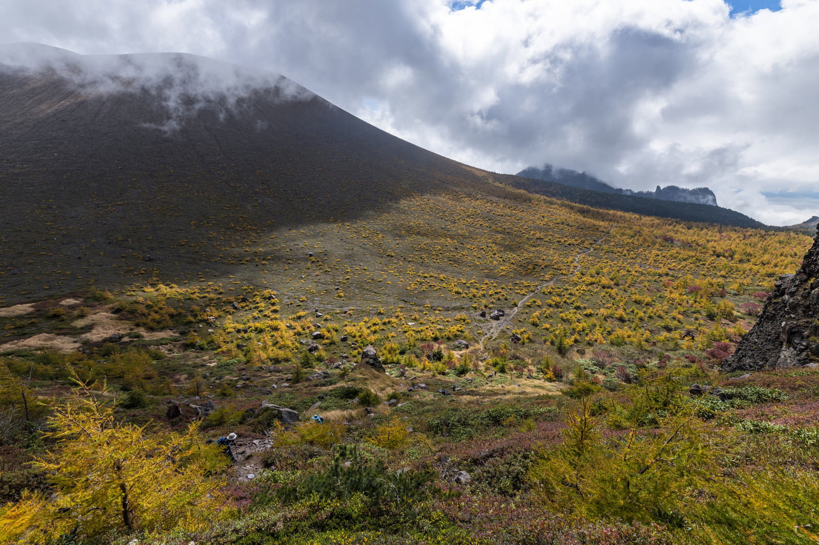 黄金色の唐松紅葉が広がる浅間山賽の河原と雲に覆われた山容