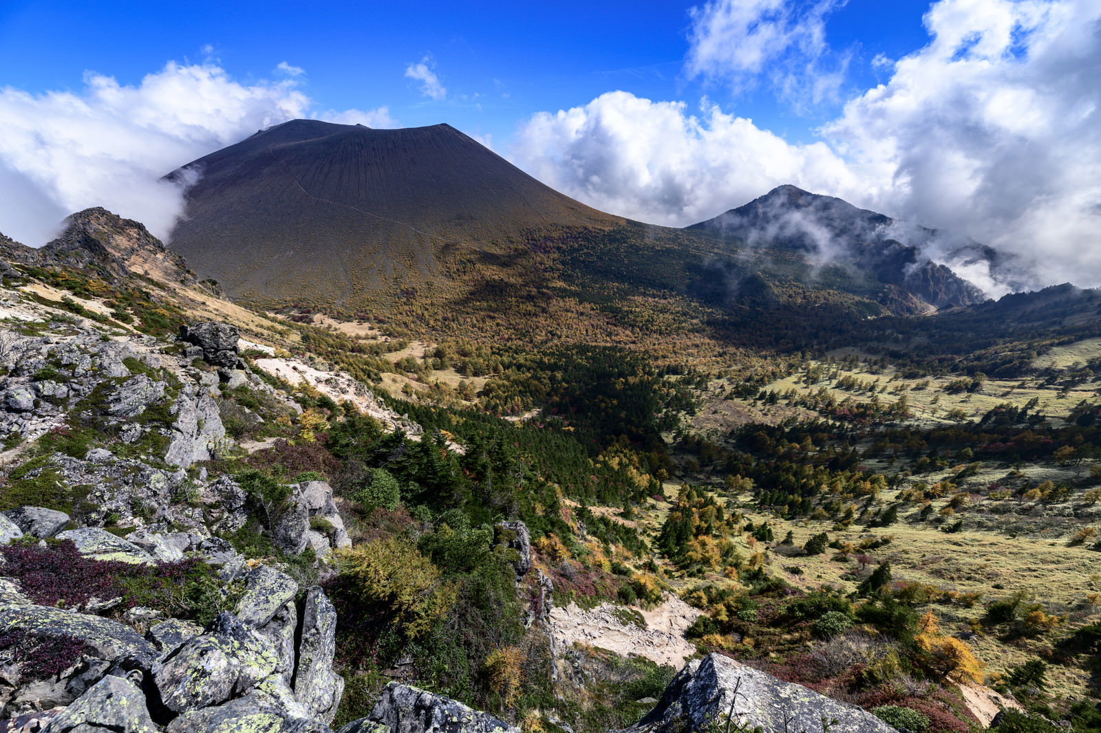 青空の下に広がる浅間山の紅葉風景、岩場と色づいた木々が美しい山岳写真