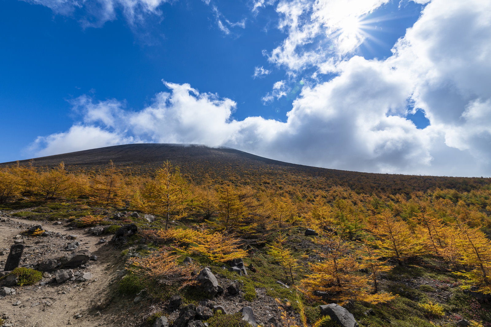 青空と雲の下で紅葉に色づく浅間山本体の山岳風景