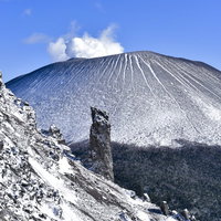 鞘ヶ峰の稜線から望む雪化粧した浅間山と岩場の登山道の写真