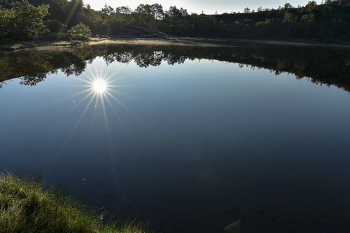 草津白根山の弓池に映り込む太陽と光芒の風景