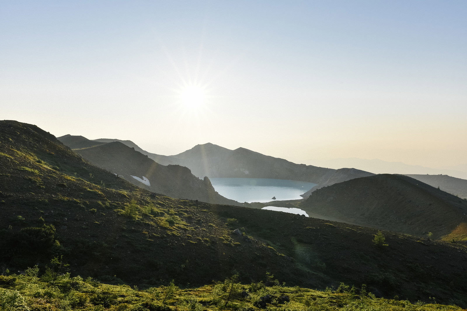 朝日を受ける草津白根山の火口湖・湯釜