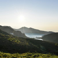 朝日を受ける草津白根山湯釜の写真