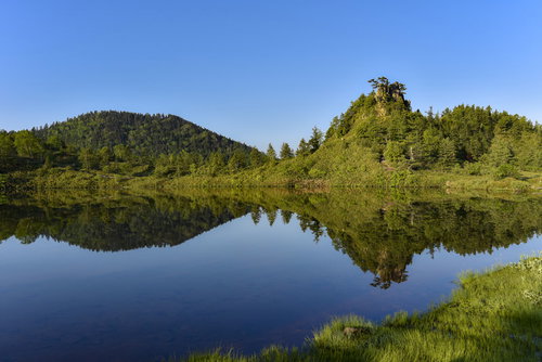 湖面に鮮明に反射する草津白根山の弓池の景色