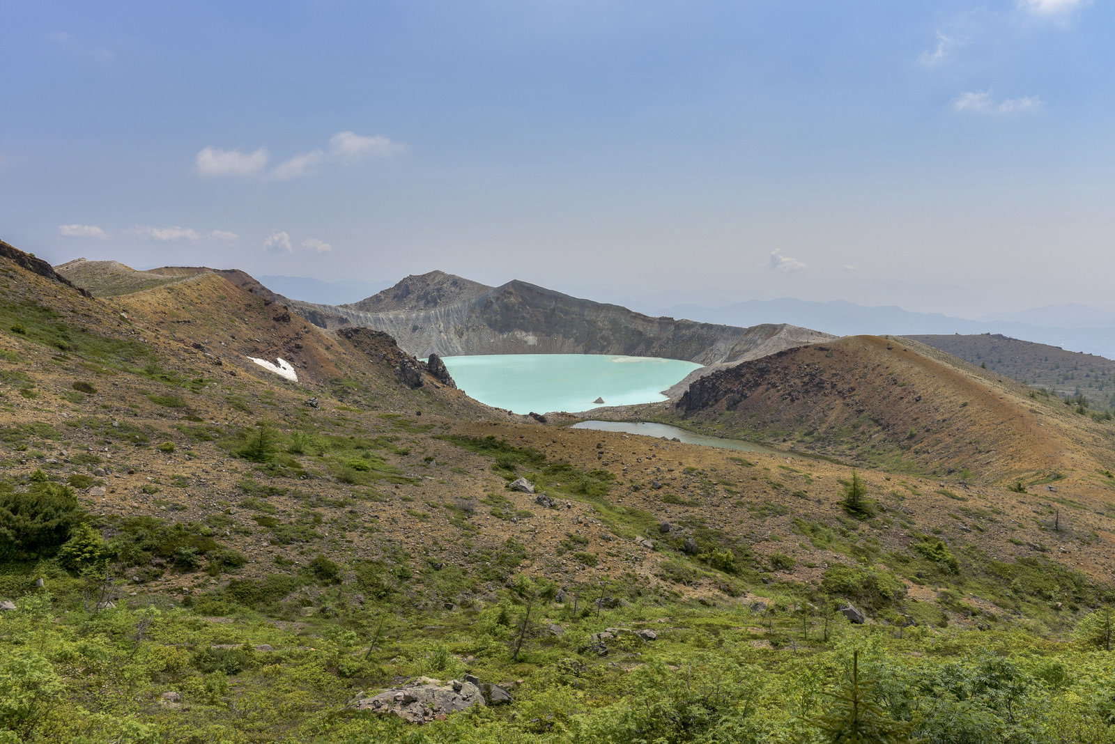 エメラルドグリーンの湯釜を中心とした草津白根山の山岳風景