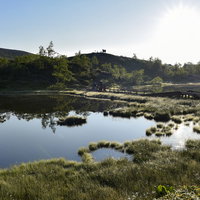 草津白根山の弓池、湖面に空と山々を映す火口湖の写真