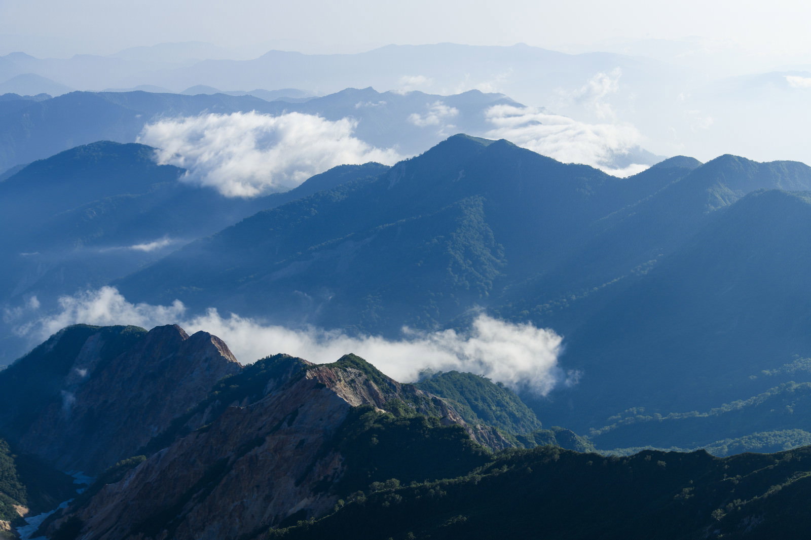 青い山並みに白い雲がかかる白山の風景写真