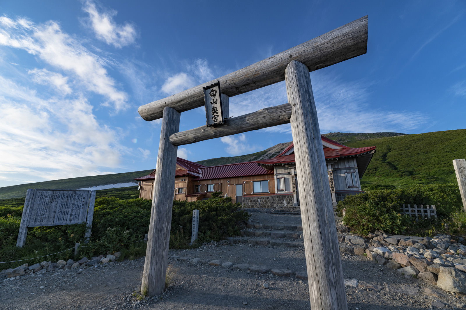 夕日に照らされる白山神社奥社の木製鳥居と青空に浮かぶ白い雲