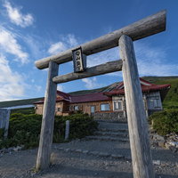 夕日に照らされる白山神社奥社の木製鳥居と山頂風景の写真