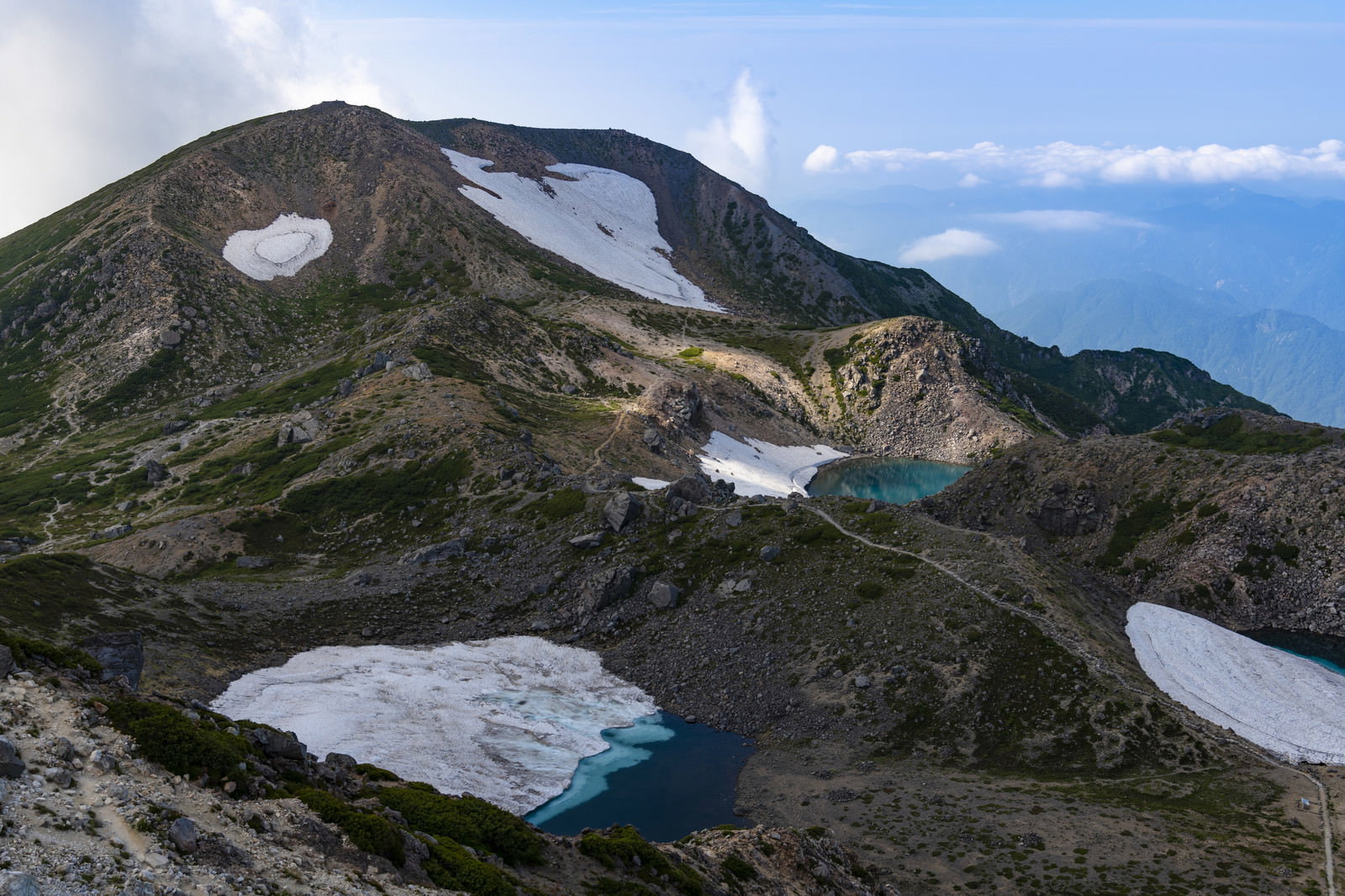 白山の御前峰から眺めた大汝峰方面の山岳風景、残雪と池が見える