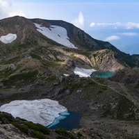 御前峰から望む大汝峰方面の残雪と池（白山）の写真