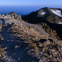 御前峰から大汝峰へと向かう登山道と岩場の稜線（白山）の写真