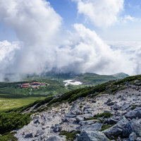 御前峰登山道から見える白山室堂小屋と緑の草原の写真
