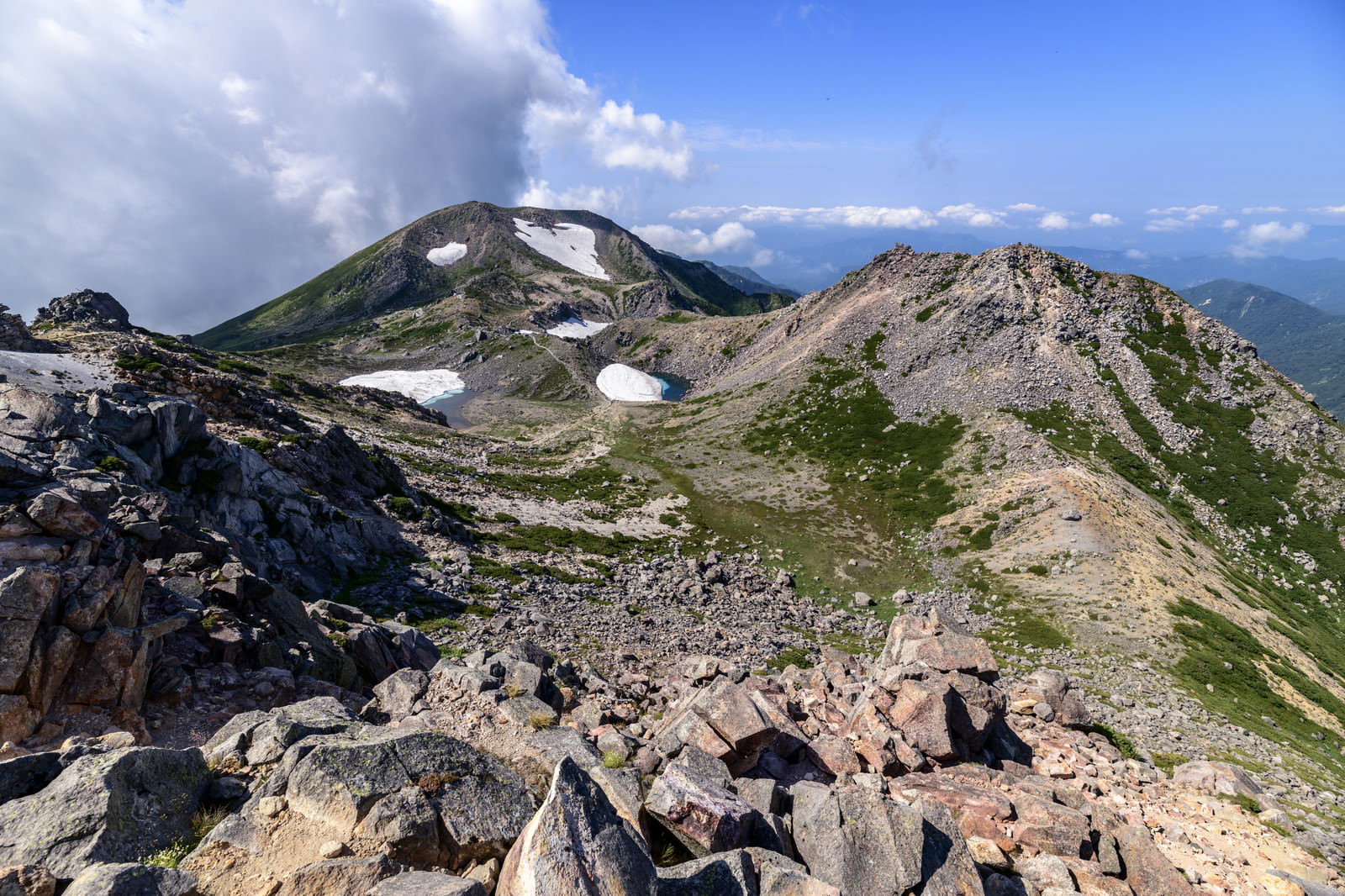 快晴の青空の下、白山山頂の岩場から見渡す荒野と山々の稜線