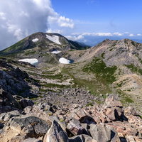 快晴の白山山頂から見渡す荒野と山々の稜線の写真