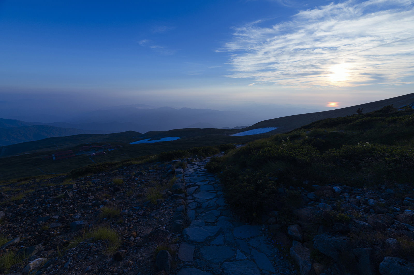 日本海に沈む夕日を背景に石畳の登山道が続く白山の風景
