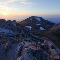 日本海に沈む夕日を眺める白山御前峰の登山者の写真