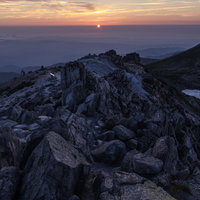 沈みゆく太陽と白山山頂の岩場 日本百名山の夕焼け風景の写真