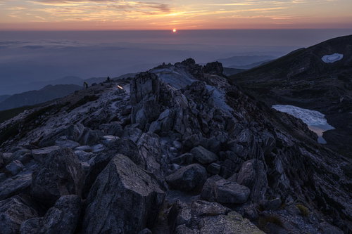 沈みゆく太陽と白山山頂の岩場 日本百名山の夕焼け風景