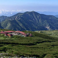 白山室堂平の赤い屋根の山荘と別山の遠景、高原風景の写真