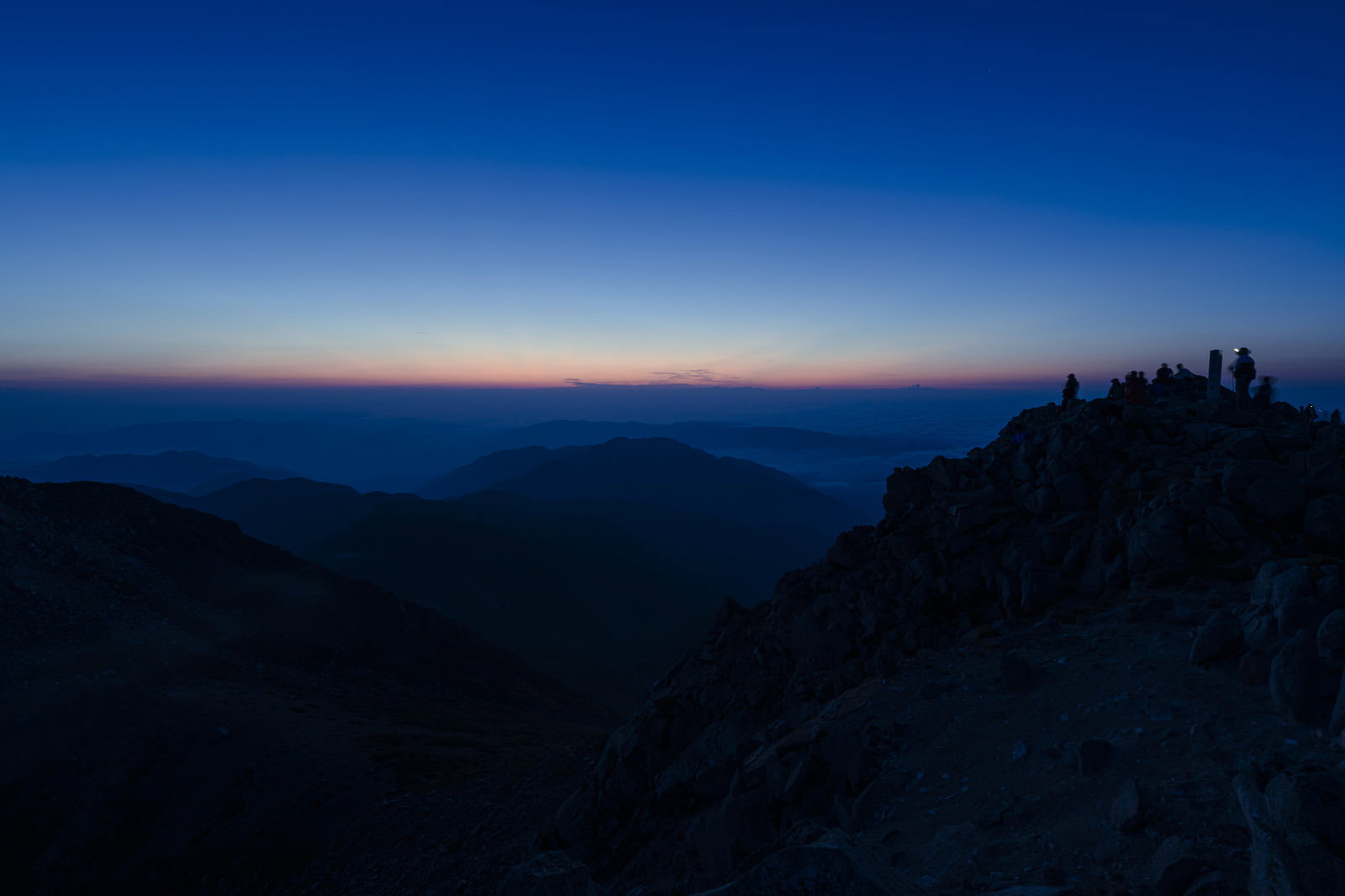 白山山頂で夜明けの朝焼けを待つ登山者たちのシルエット
