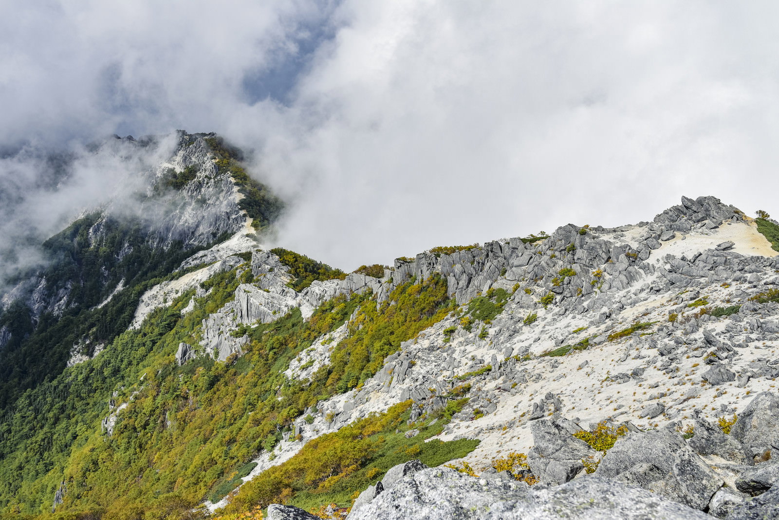 雲がかかる鳳凰山の白砂と岩の稜線を写した山岳風景