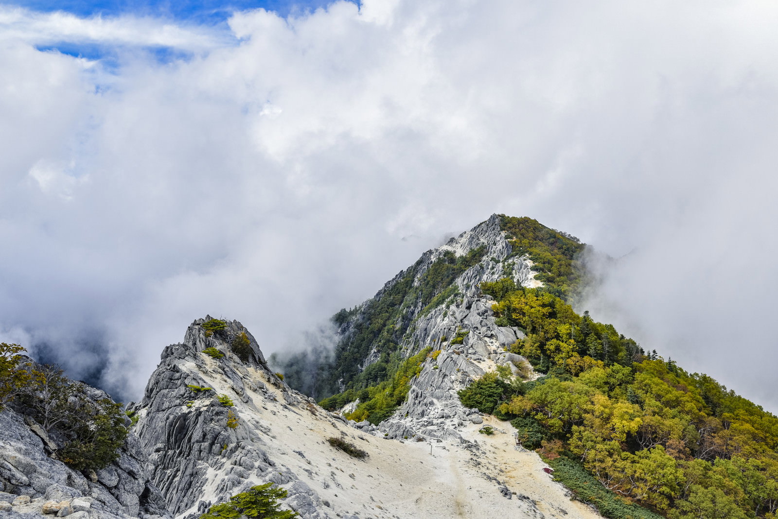 白砂が広がる鳳凰山の稜線に岩場と緑の植生、青空と雲が見える山岳風景