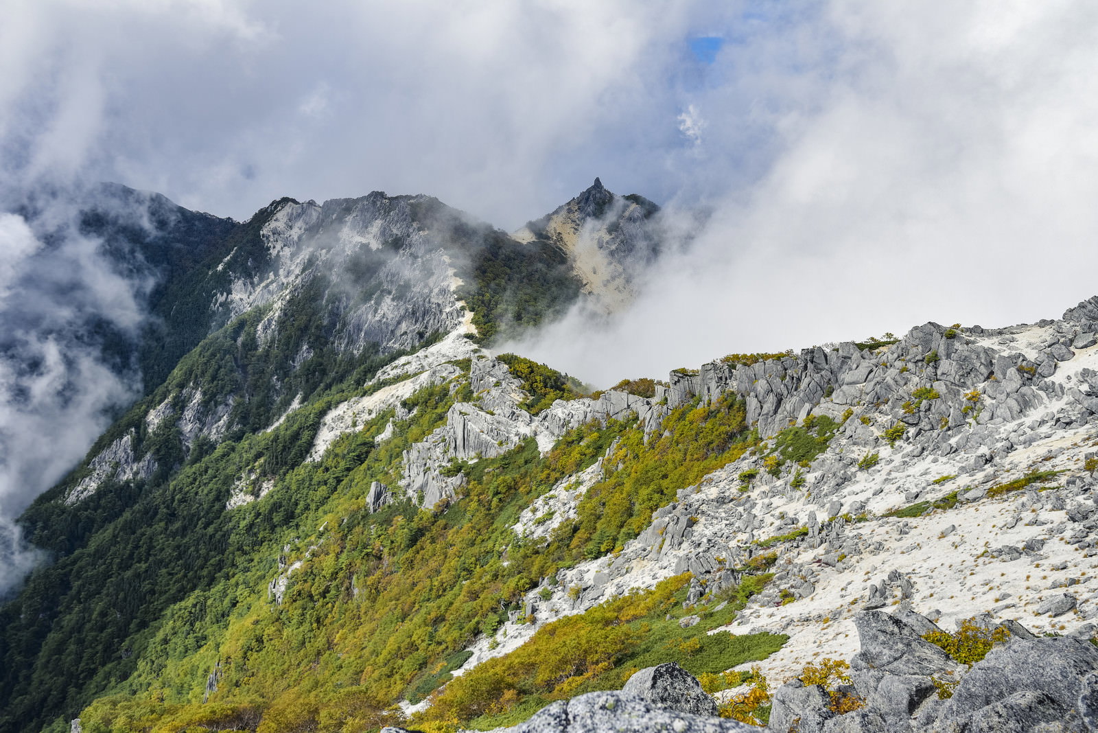 白砂の稜線から見上げる鳳凰三山のオベリスクが雲海の向こうに聳える山岳風景