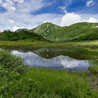 天狗の庭の池塘に映る青空と雲、背景に火打山（ひうちやま）の写真